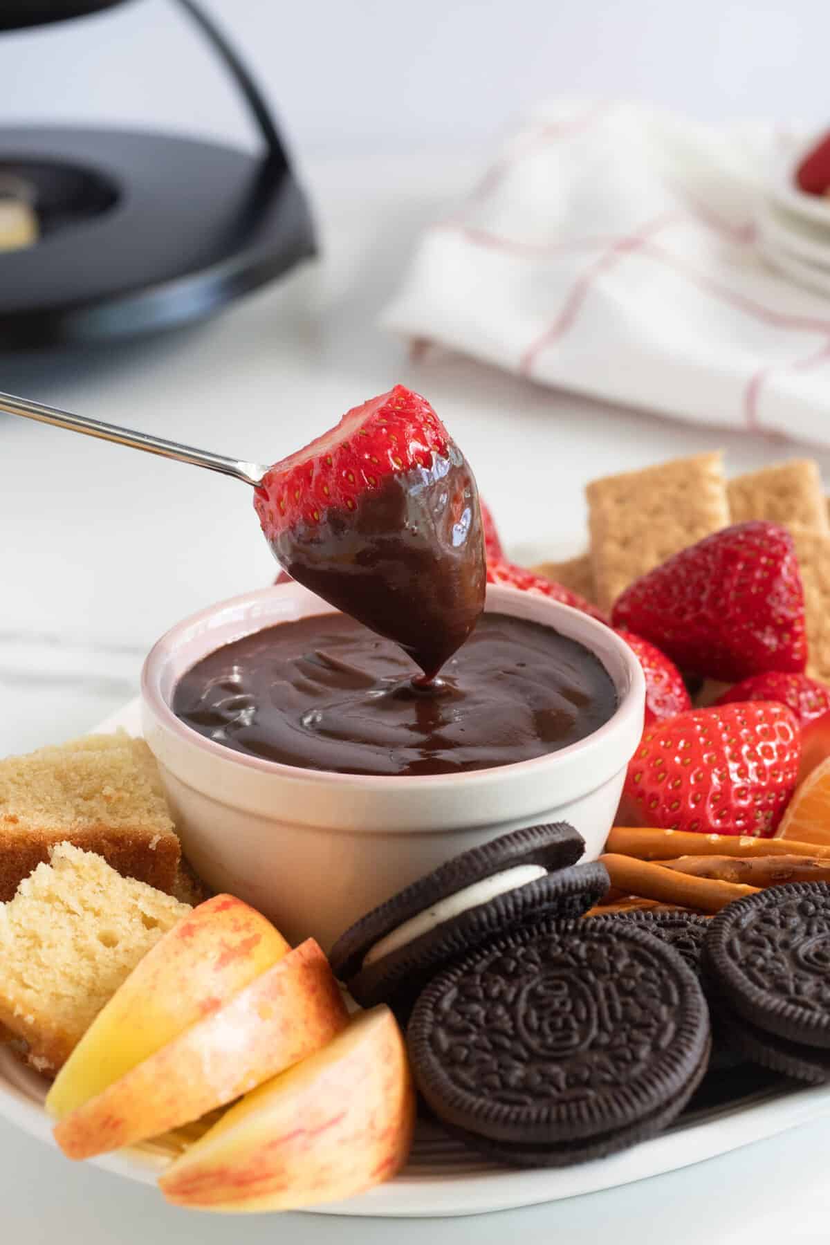 a strawberry being dipped in chocolate fondue 