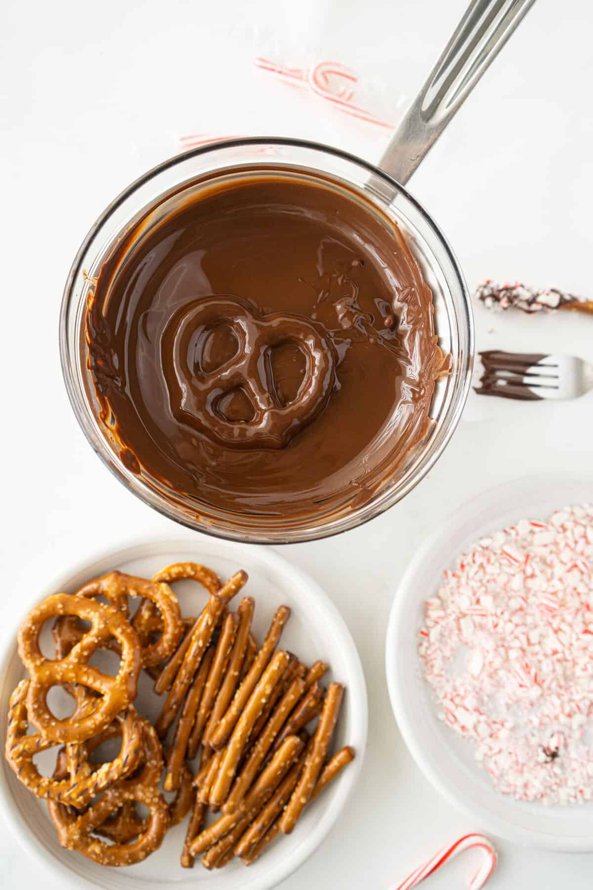 dipping a pretzel into a bowl of melted chocolate 