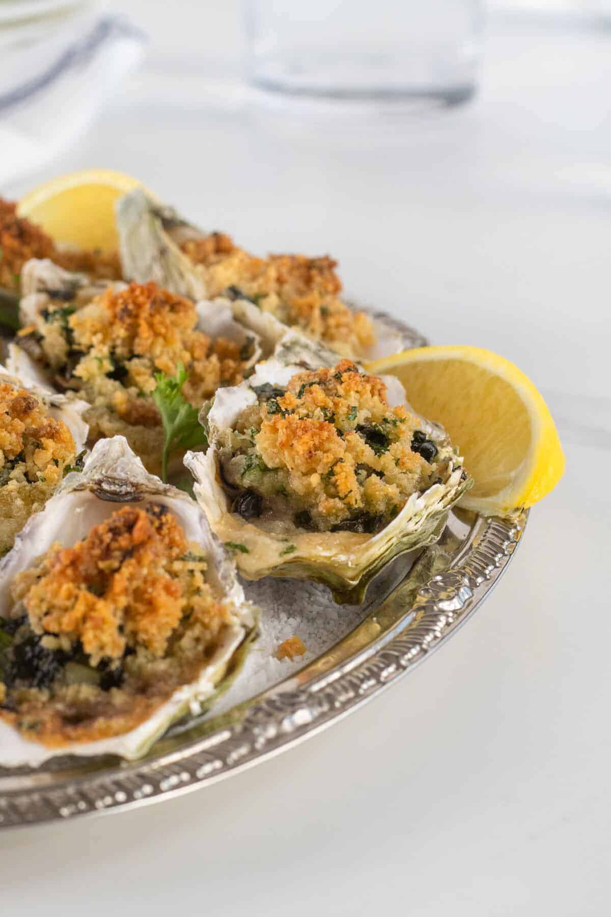 oysters Rockefeller on a silver platter with lemons