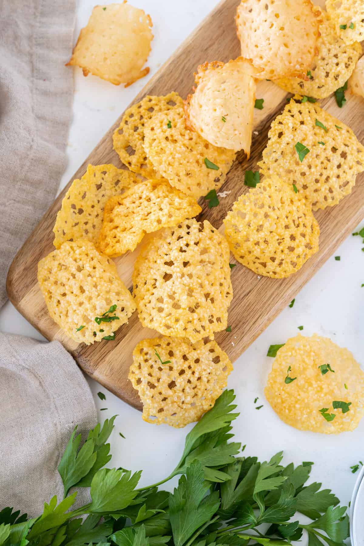 a pile of Parmesan crisps on a wooden board 