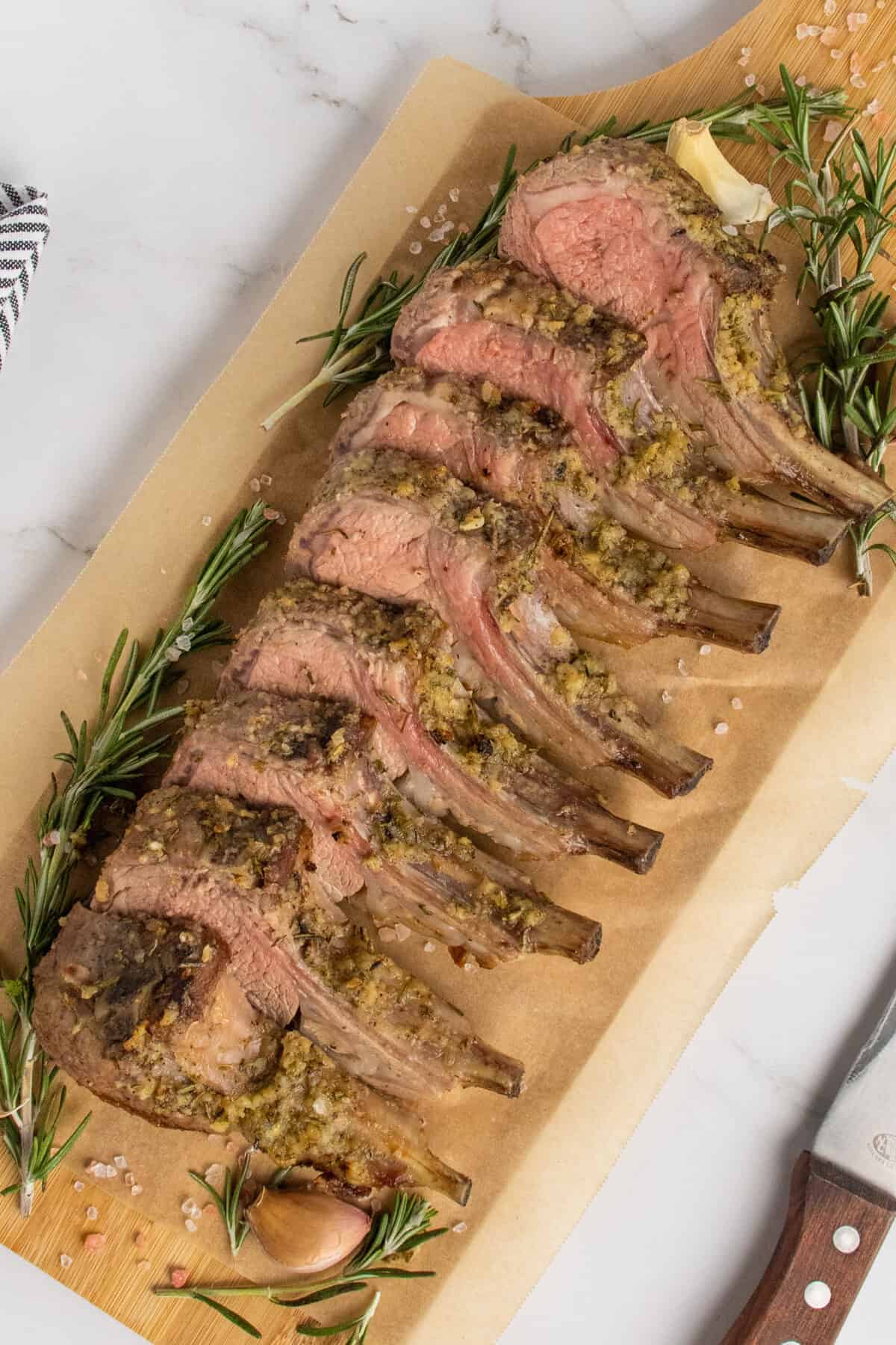 roasted rack of lamb sliced on a wooden cutting board