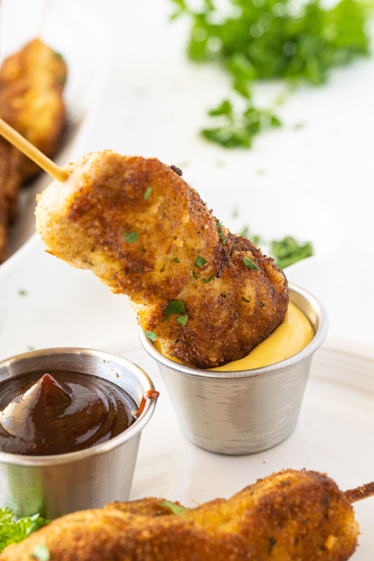 dipping city chicken skewers into honey mustard sauce