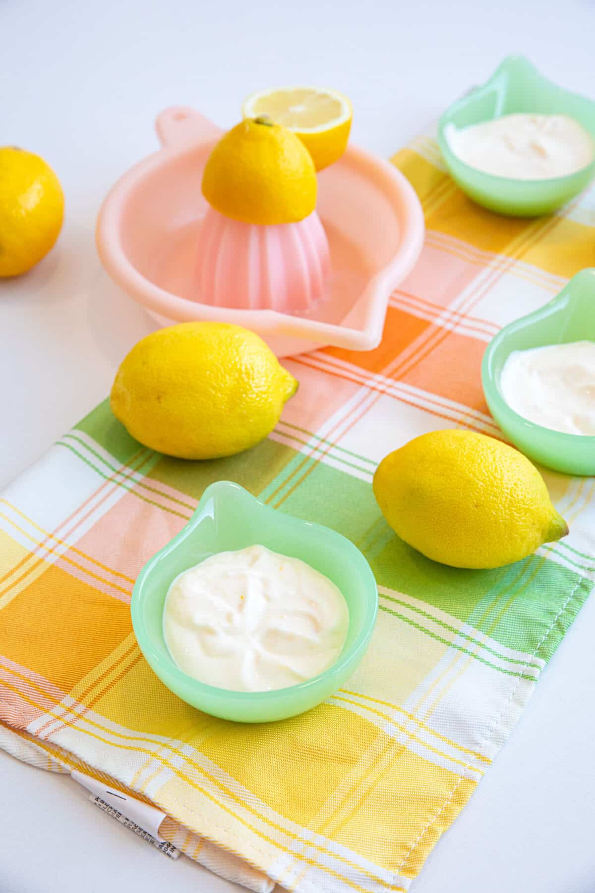 Lemon Aioli in a small bowl with 2 lemons around the bowl