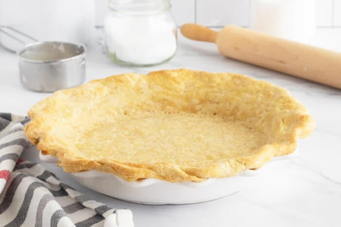 Pie crust in pie plate with rolling pin beside it