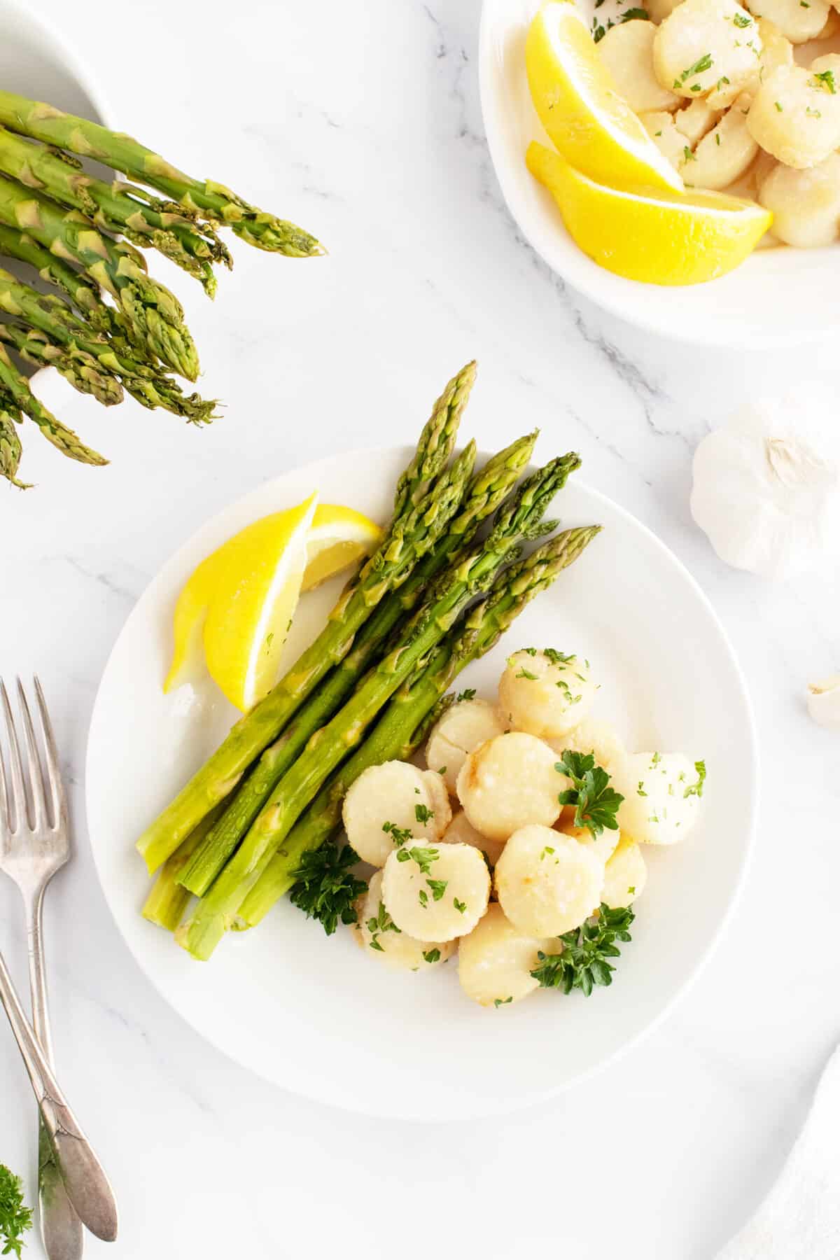 Broiled scallops on a white plate with asparagus