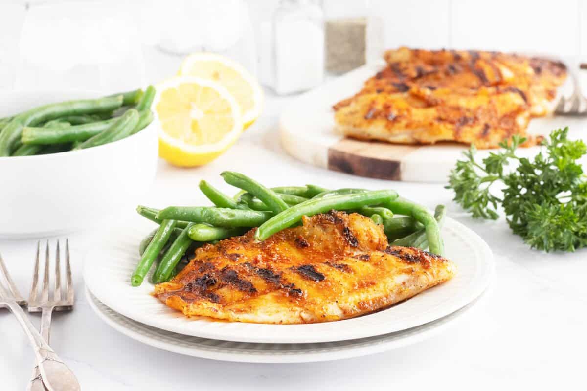 Grilled tilapia on a plate with green beans