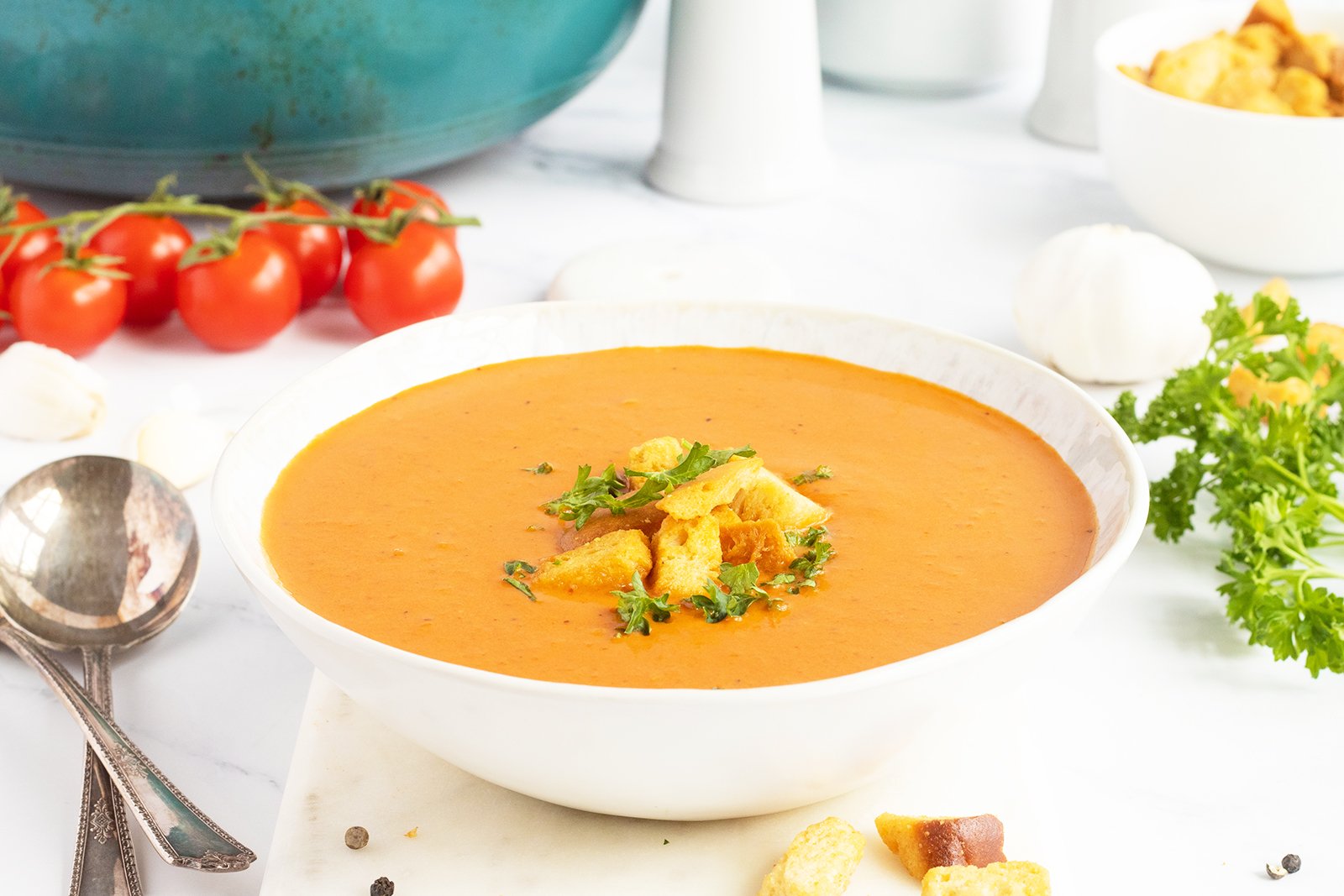 Creamy tomato bisque served in a bowl with herbs.