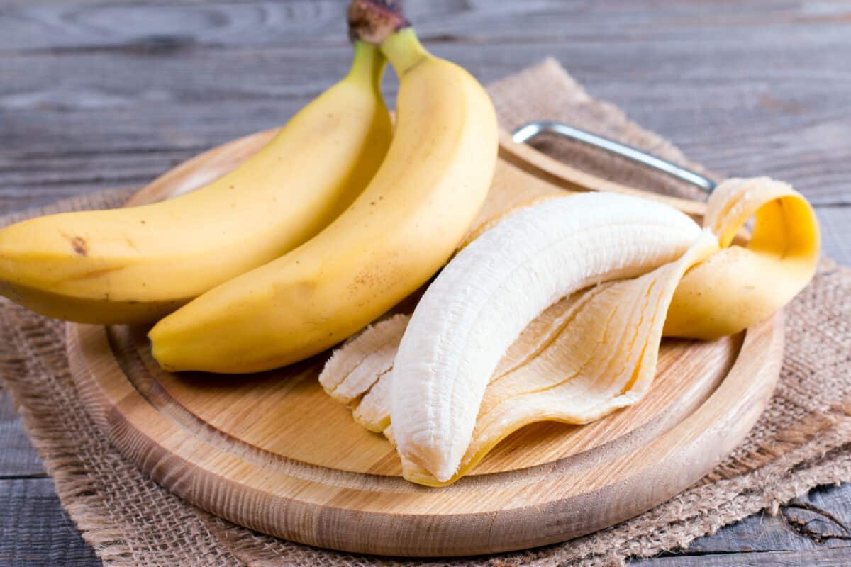 yellow bananas on a wooden cutting board