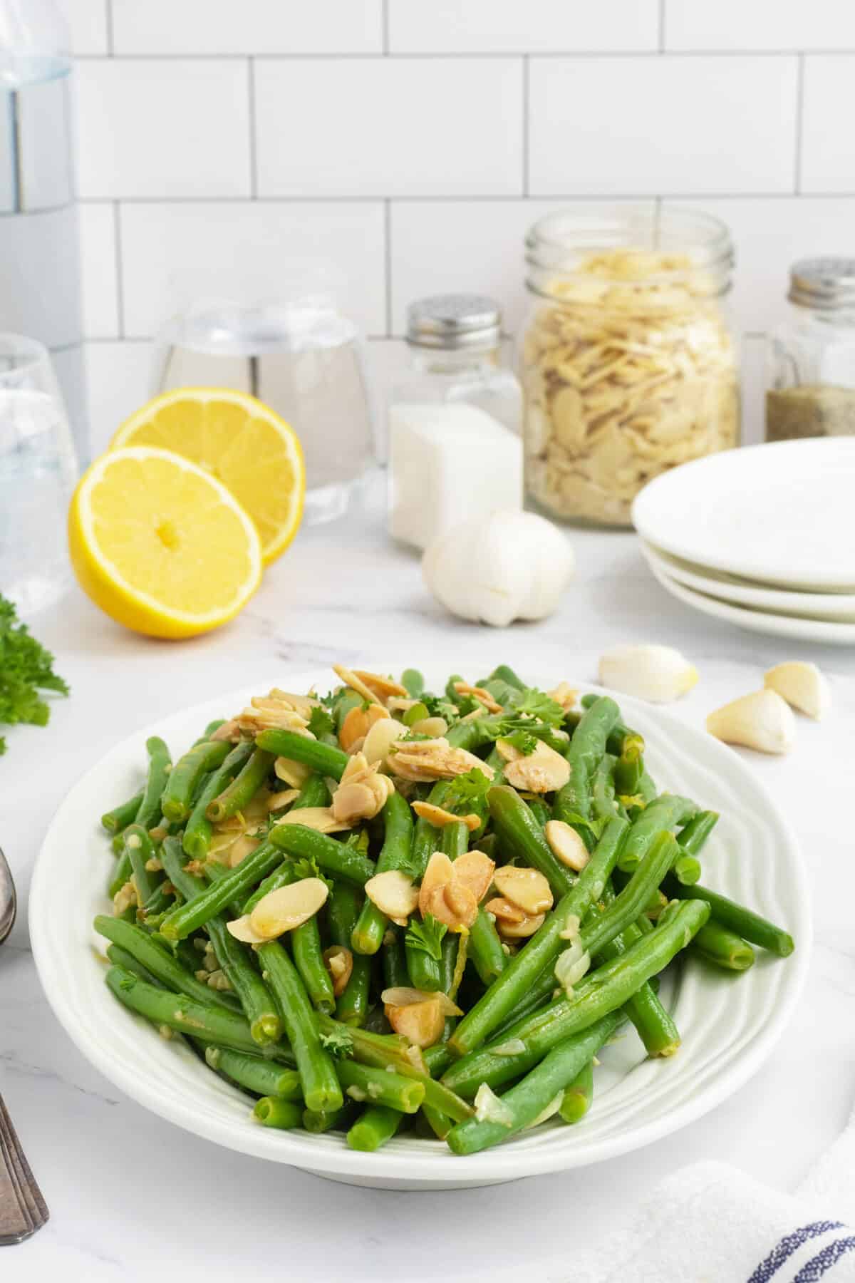 green beans almondine on a platter with a lemon beside it