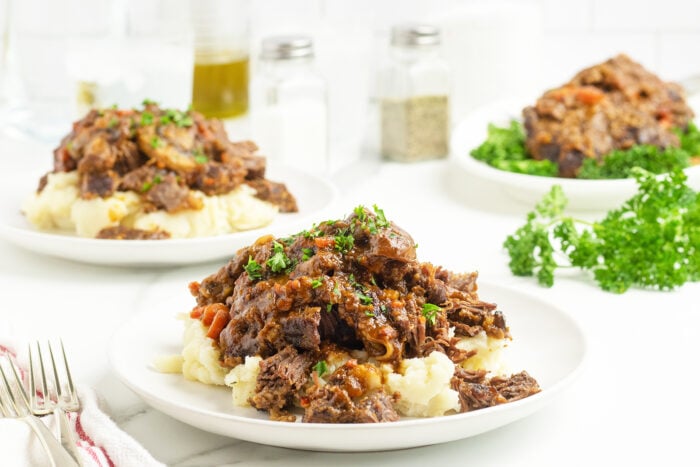 beef cheeks on mashed potatoes on a white plate