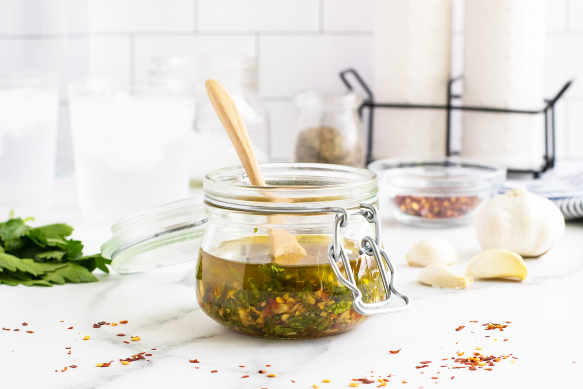 Chimichurri in a jar with a wooden spoon