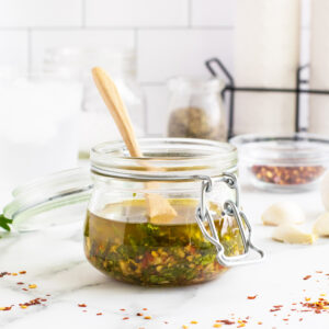Chimichurri in a jar with a wooden spoon