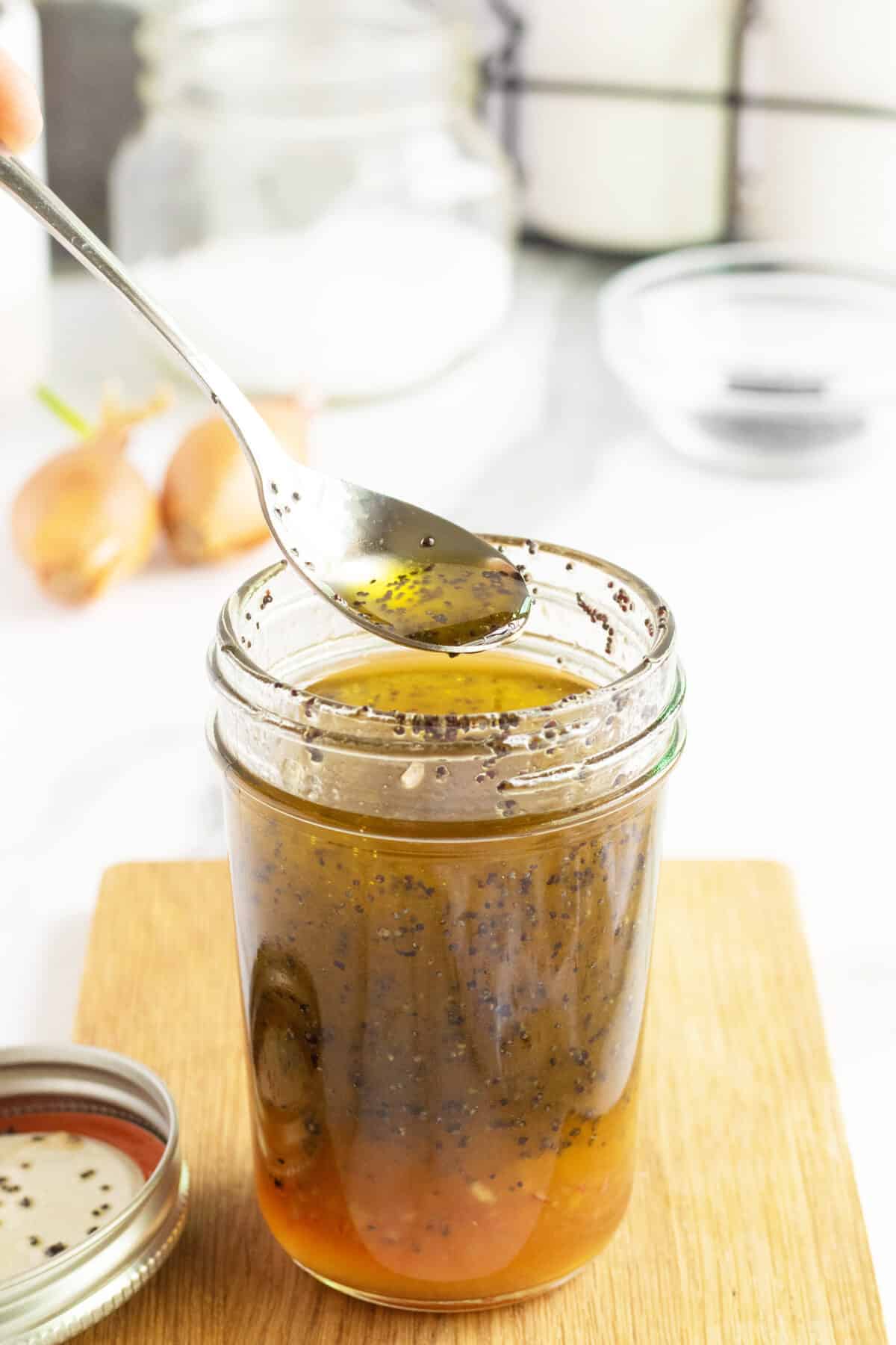 poppy seed dressing in a maspn jar with a spoon full of dressing