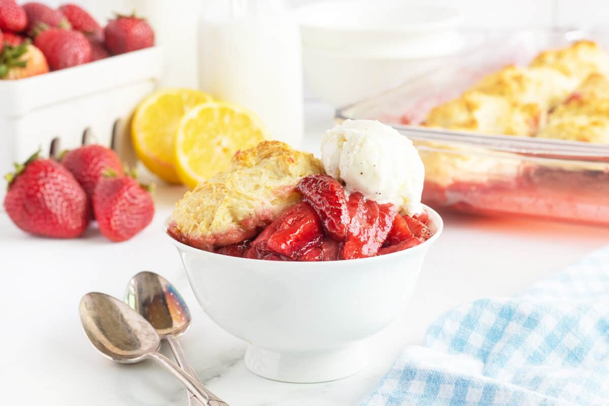 Strawberry Cobbler in a white bowl with ice cream on top