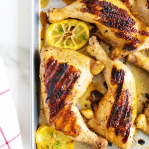 chicken marinated and grilled with slices of lemon on a pan