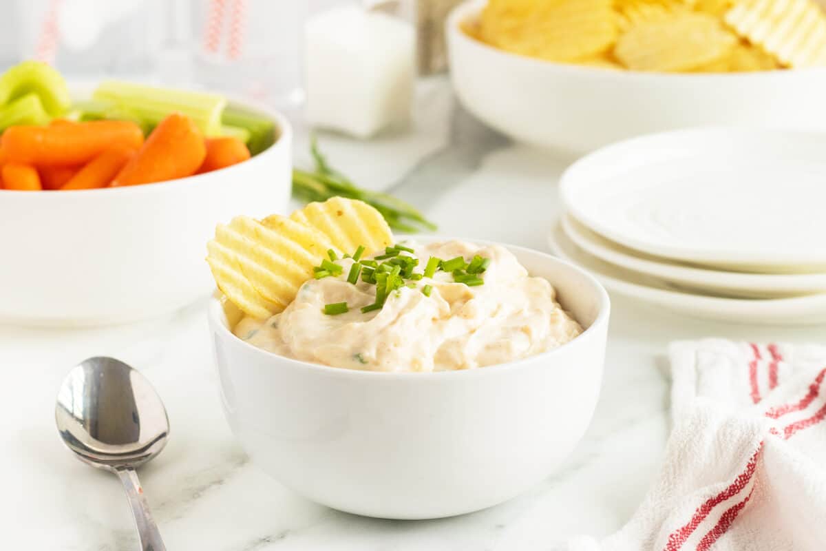 french onion dip in a white bowl with a potato chip