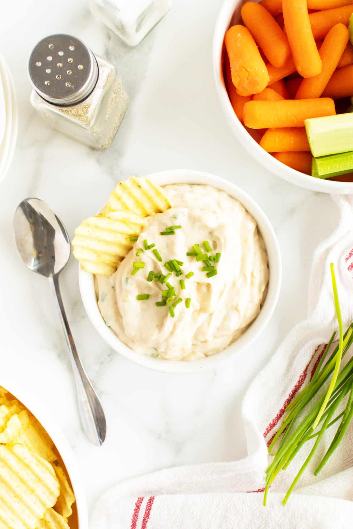 french onion dip in a bowl with a potato chip and chives