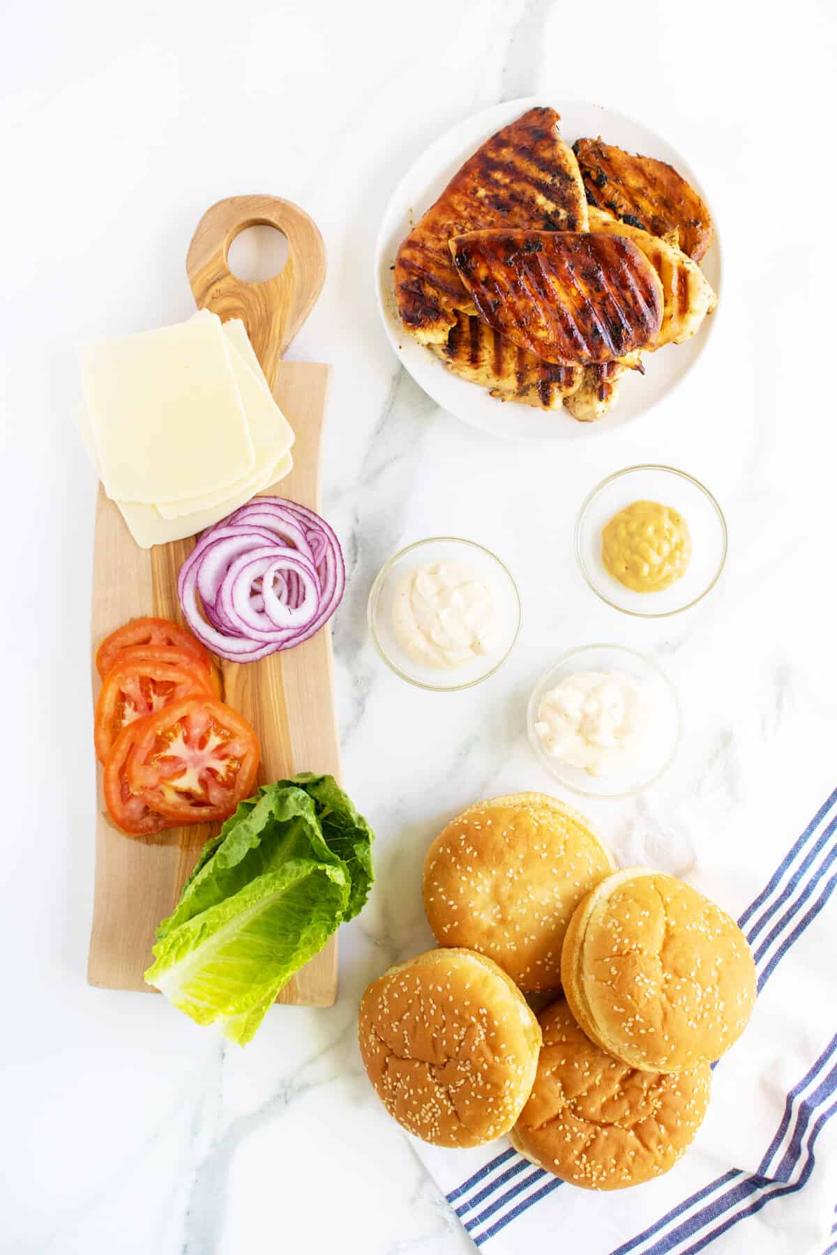 grilled chicken sandwichingredients in small bowls sliced up