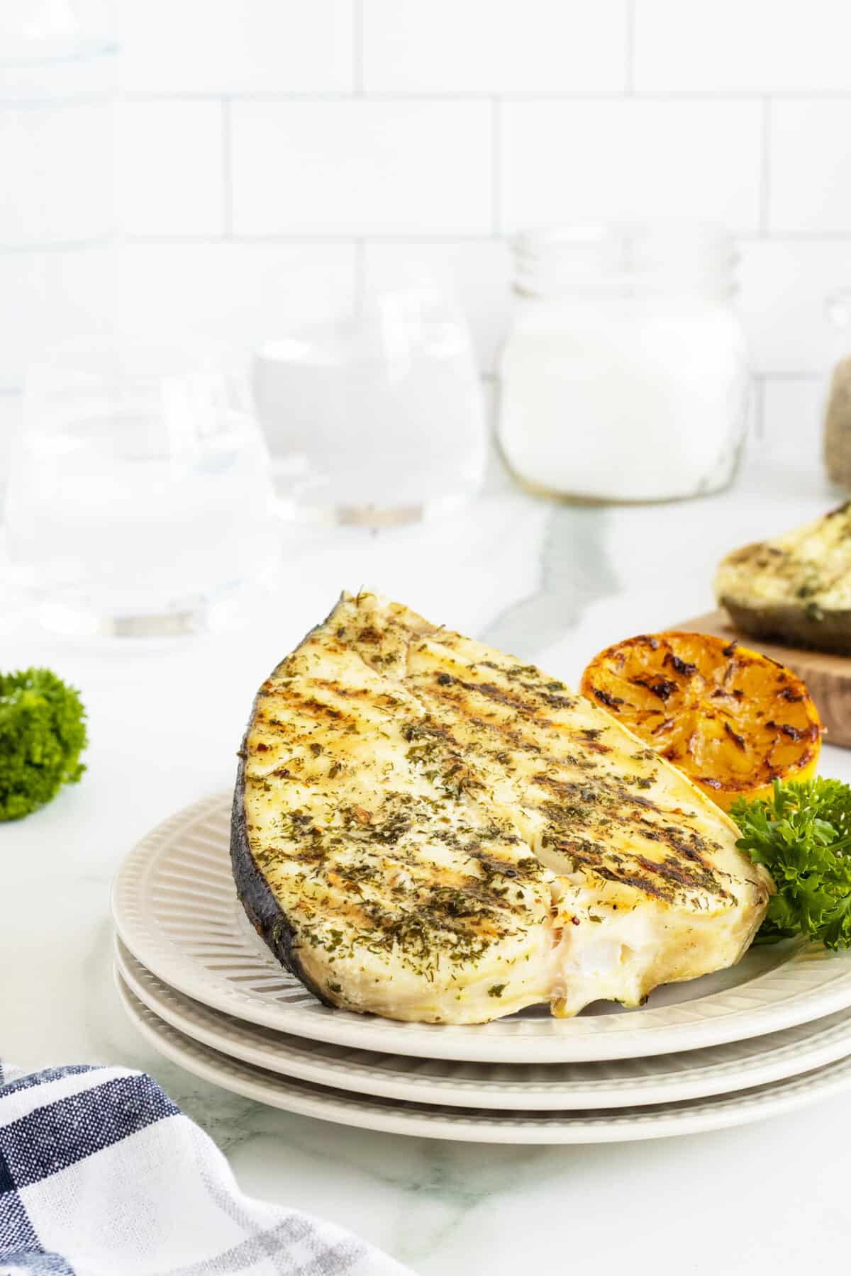 Grilled halibut on stacked white plates 