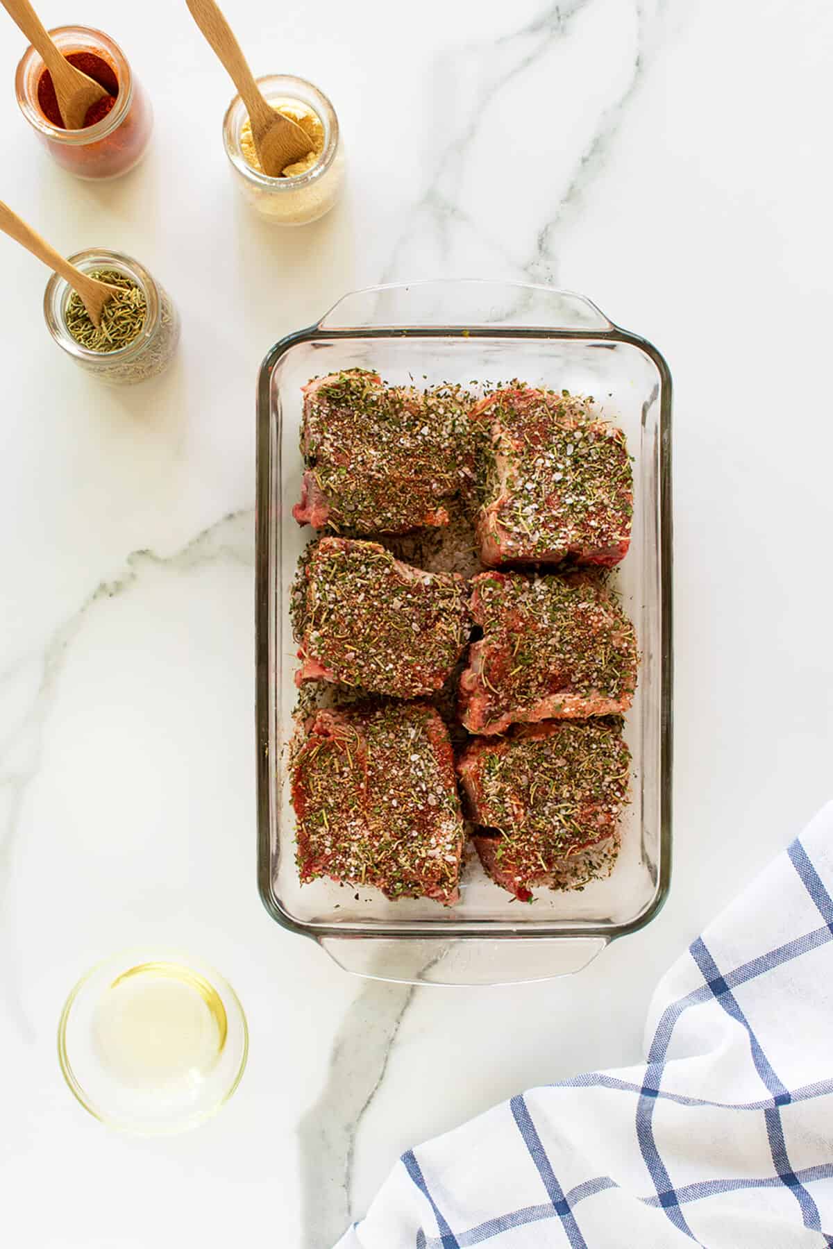 Raw lamb chops in a baking pan with seasoning