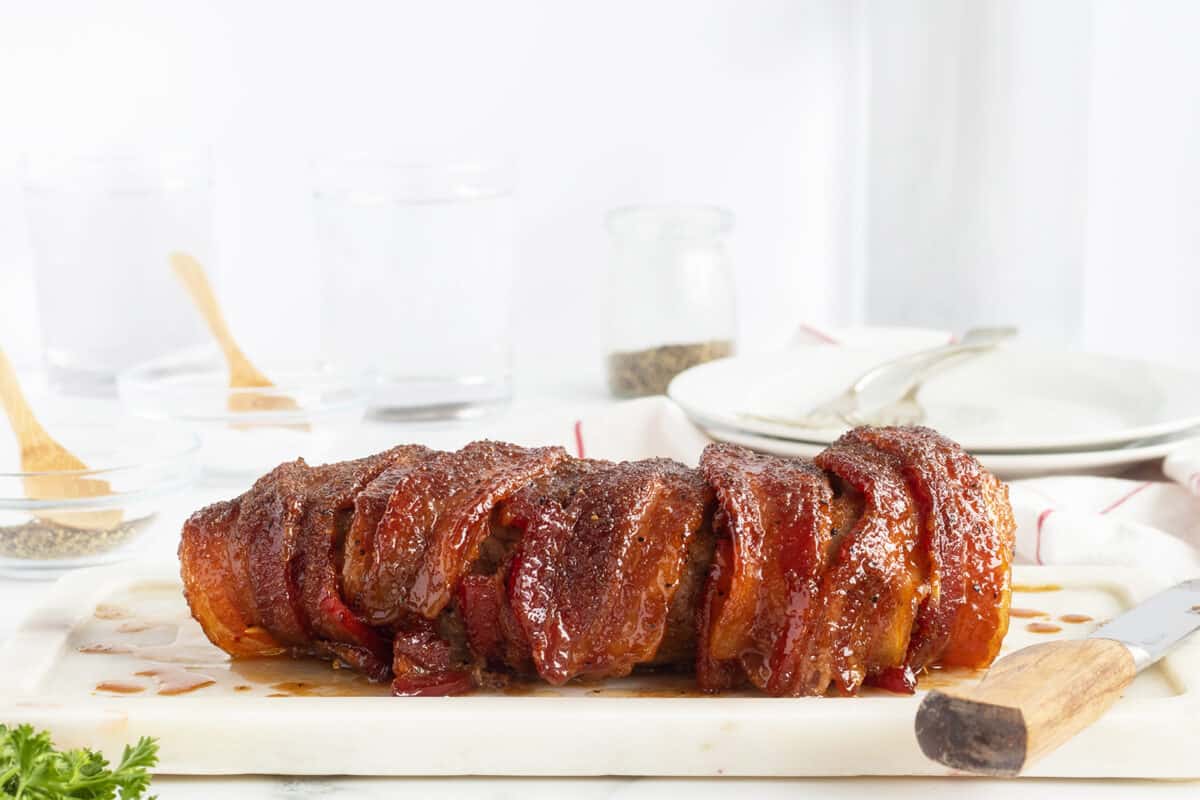 bacon wrapped pork loin on a white plate un cut
