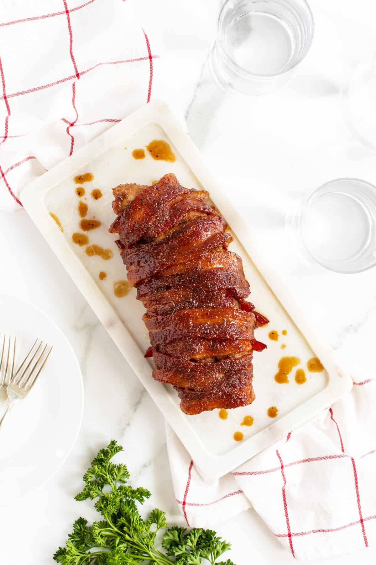 bacon wrapped pork tenderloin on a long white platter