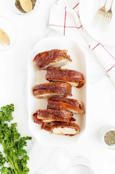 bacon wrapped pork tenderloin sliced on a long white platter