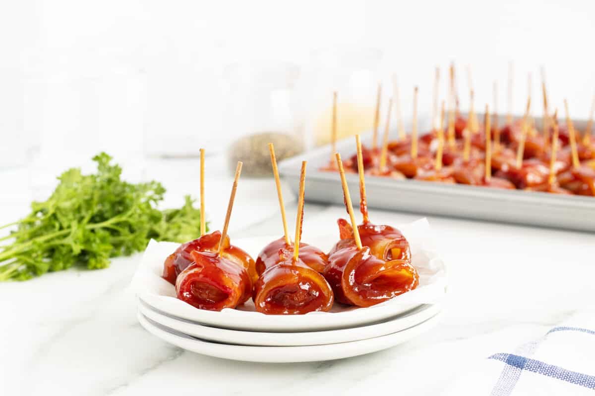 bacon wrapped water chestnuts on a stack of white plates