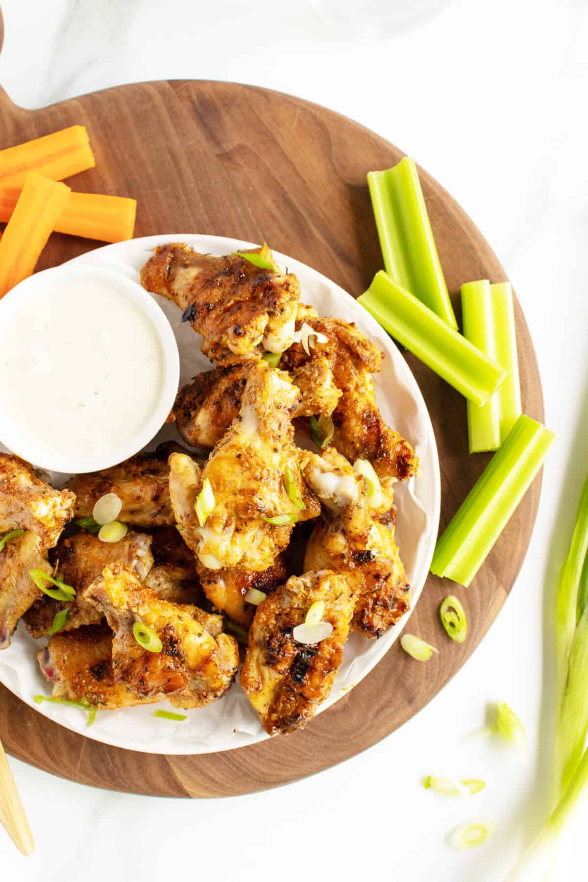 grilled chicken wings on a white plate with ranch dip