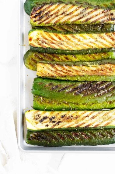 grilled zucchini lined up on a pan