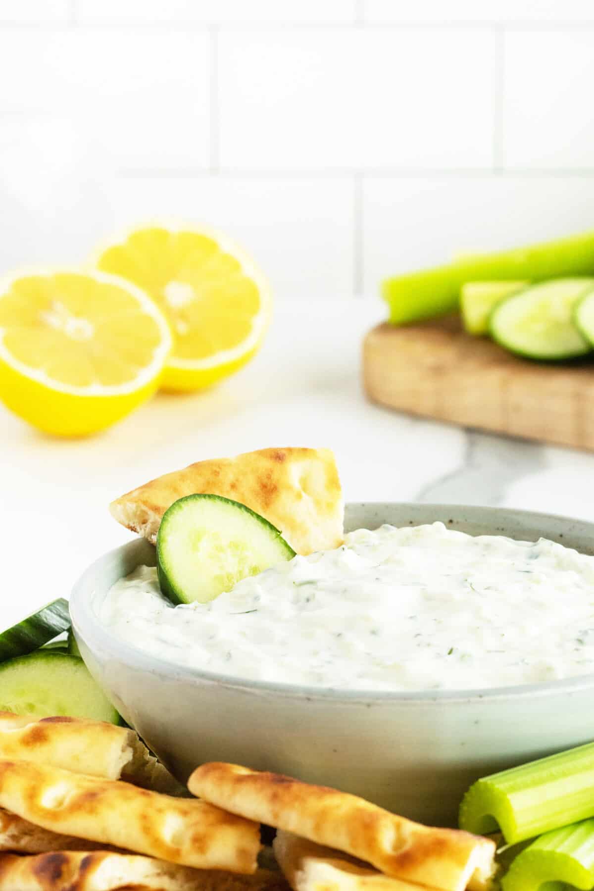 tzatziki sauce in a white bowl with a chip and cucumber in the bowl