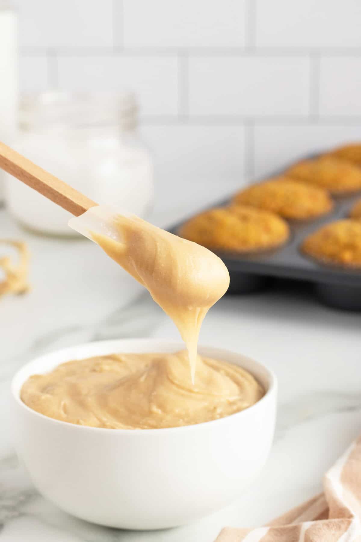 maple frosting on a spatula over a bowl