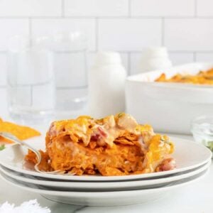 Doritos chicken casserole on a stack of white plates