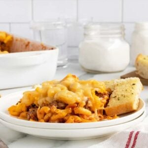 mac and cheese lasagna on a white plate with garlic bread