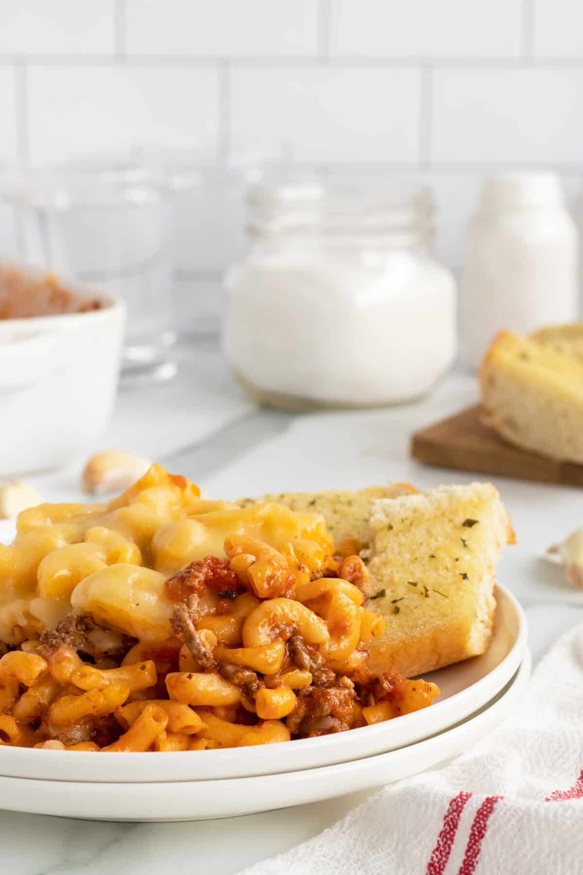 mac and cheese lasagna on a white plate with garlic bread