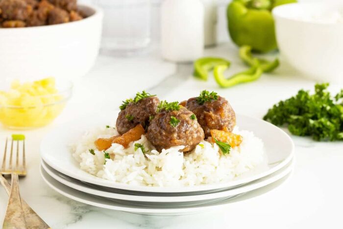 Hawaiian meatballs on top of rice on a white plate