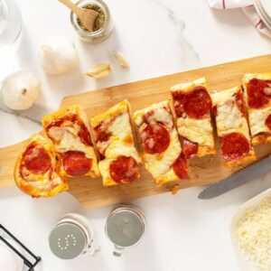 French Bread Pizza sliced on a wooden cutting board