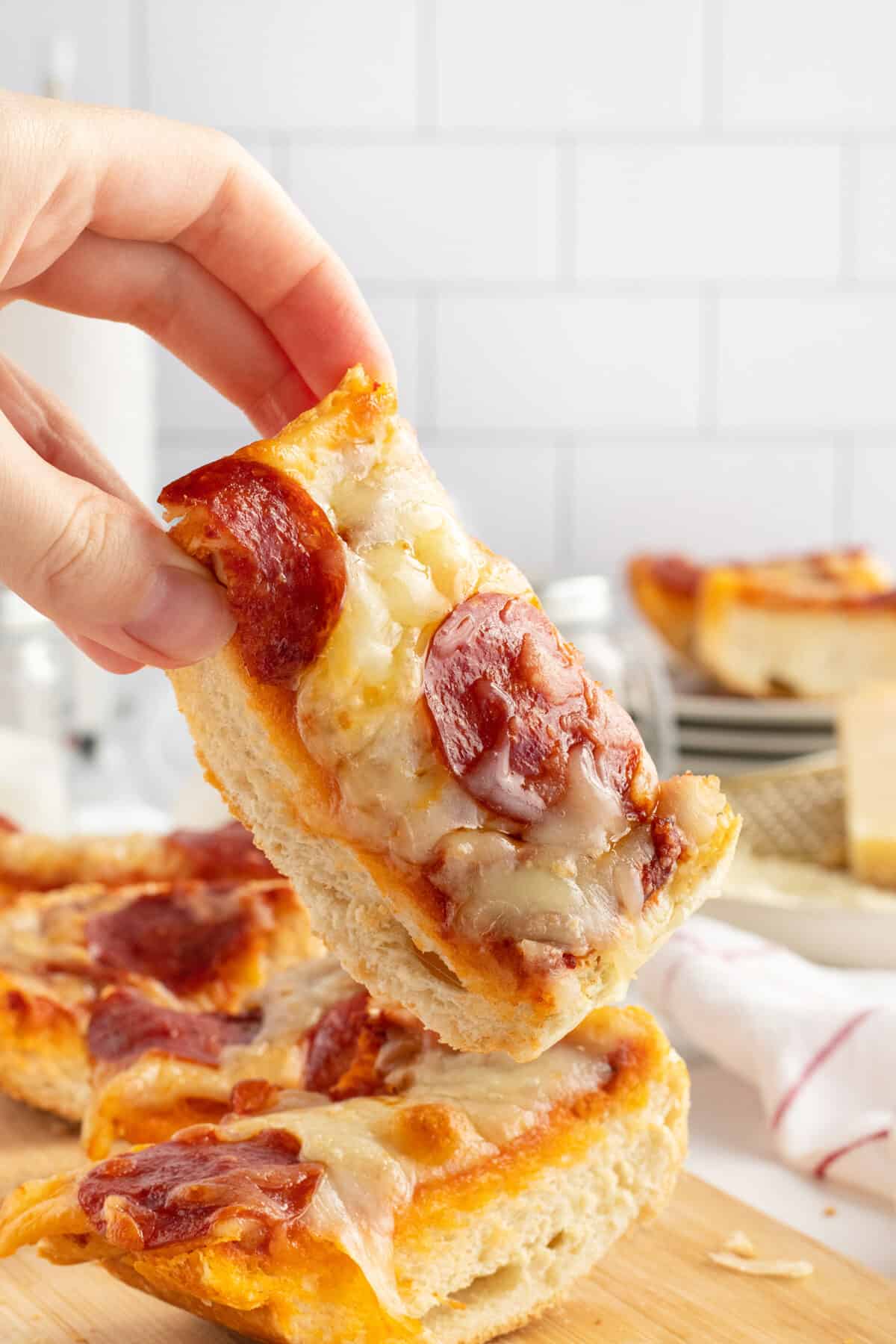 French Bread Pizza slice being held up by a hand