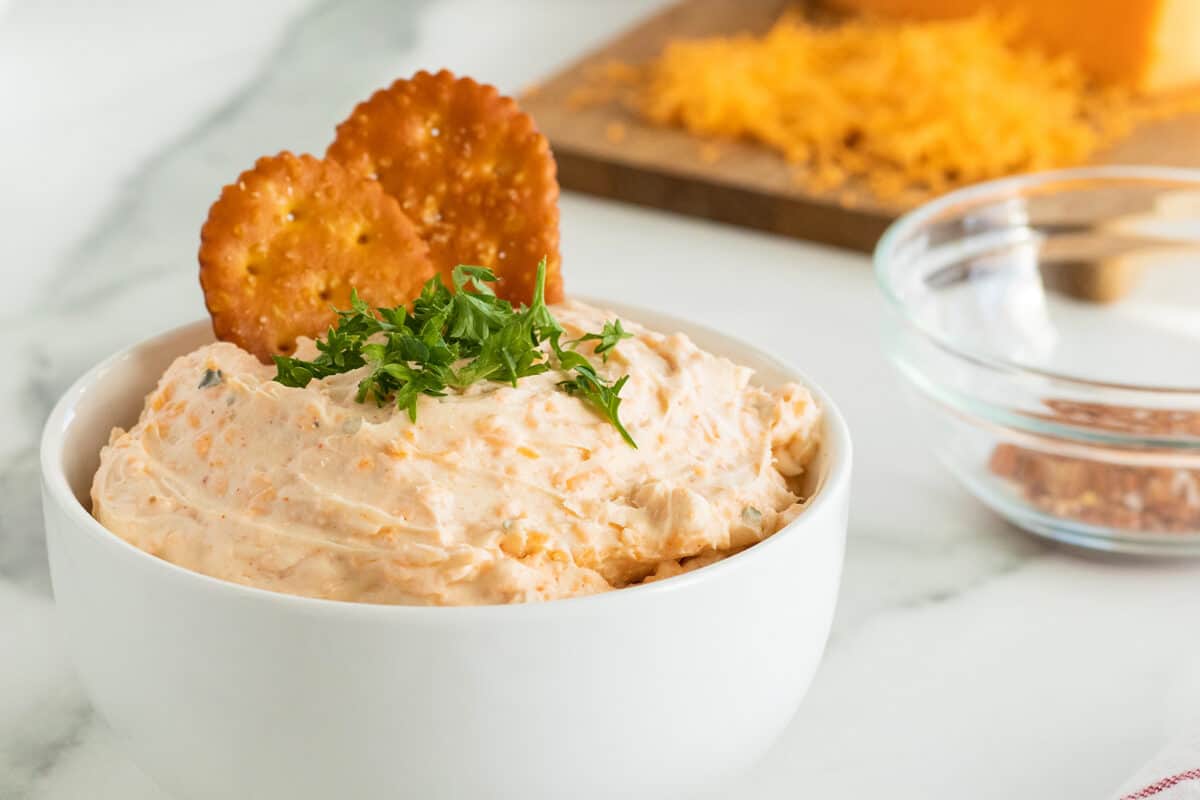 beer cheese dip in a deep white bowl with parsley sprinked on top