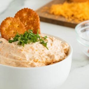 beer cheese dip in a deep white bowl with parsley sprinked on top
