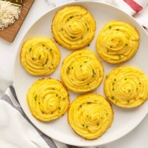 duchess potatoes on a white plate with green garnish