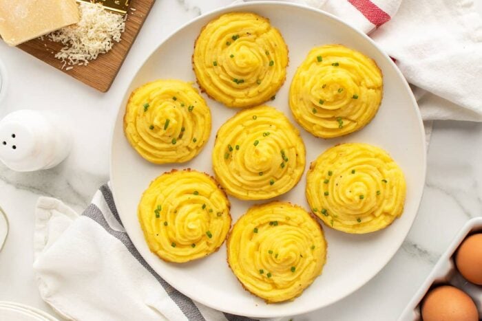 duchess potatoes on a white plate with green garnish