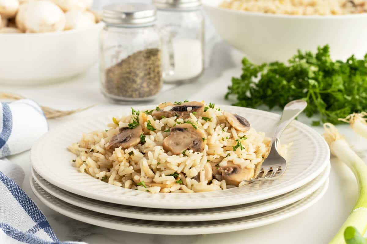 mushroom rice on a stack of white plates