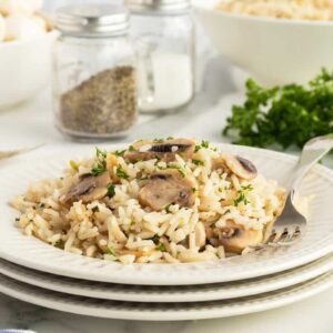 mushroom rice on a stack of white plates