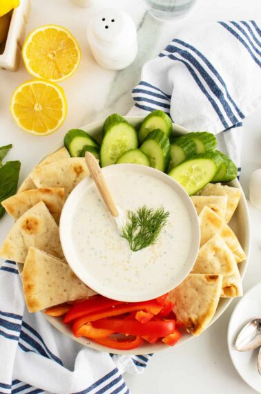 Whipped Feta Dip in a bowl on a platter with chips and sliced vegetables