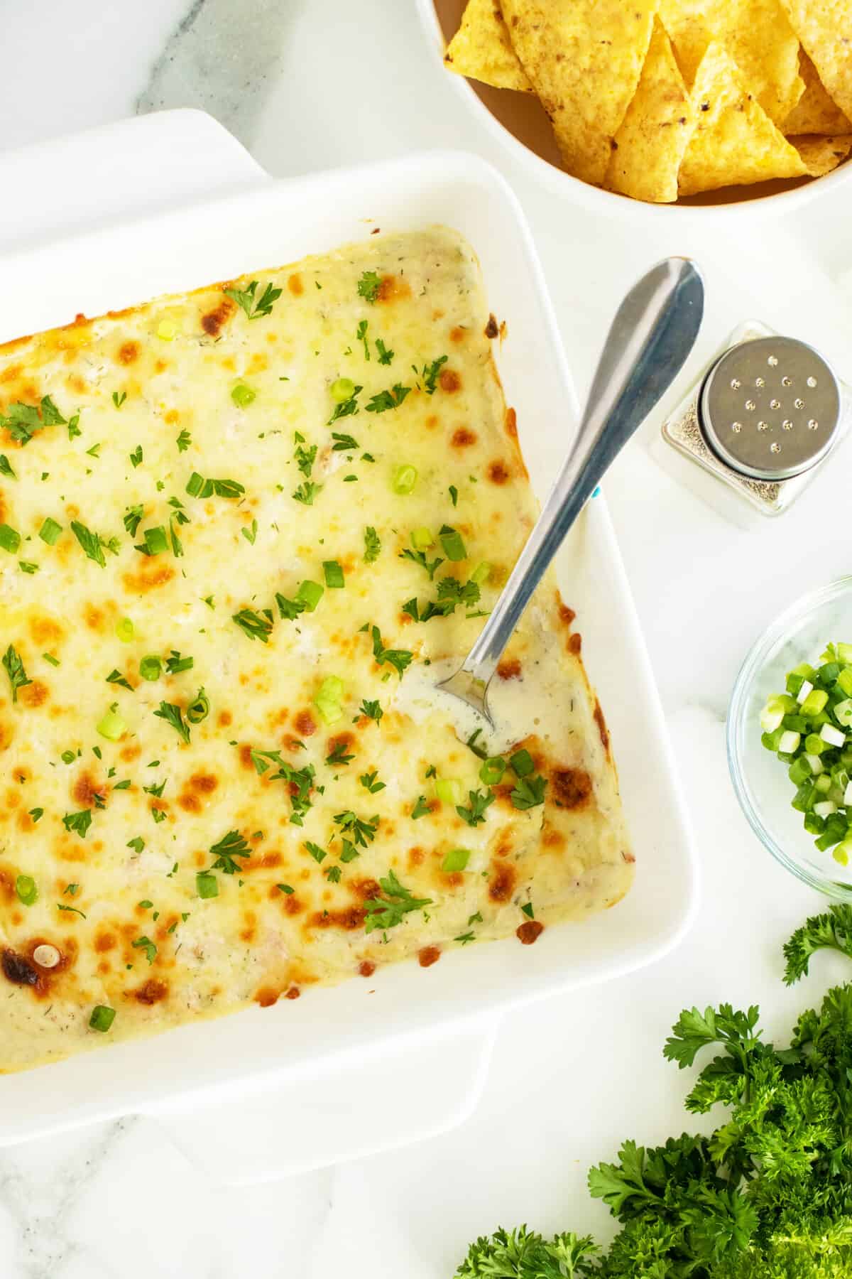 Shrimp dip in a white baking dish with a spoon