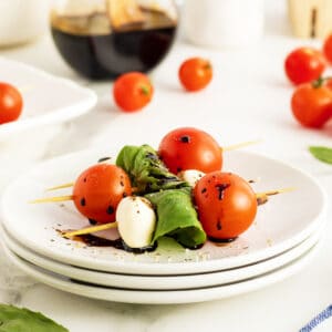 caprese skewers on a stack of white plates