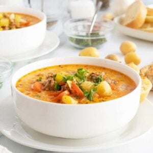 creamy sausage potato soup in a white bowl on a white plate