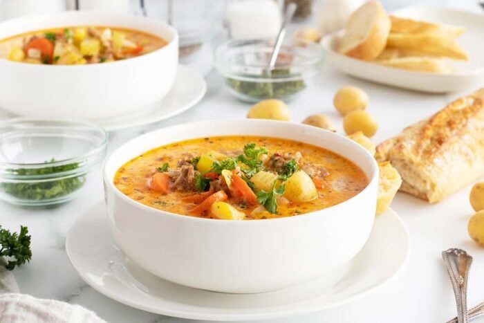 creamy sausage potato soup in a white bowl on a white plate