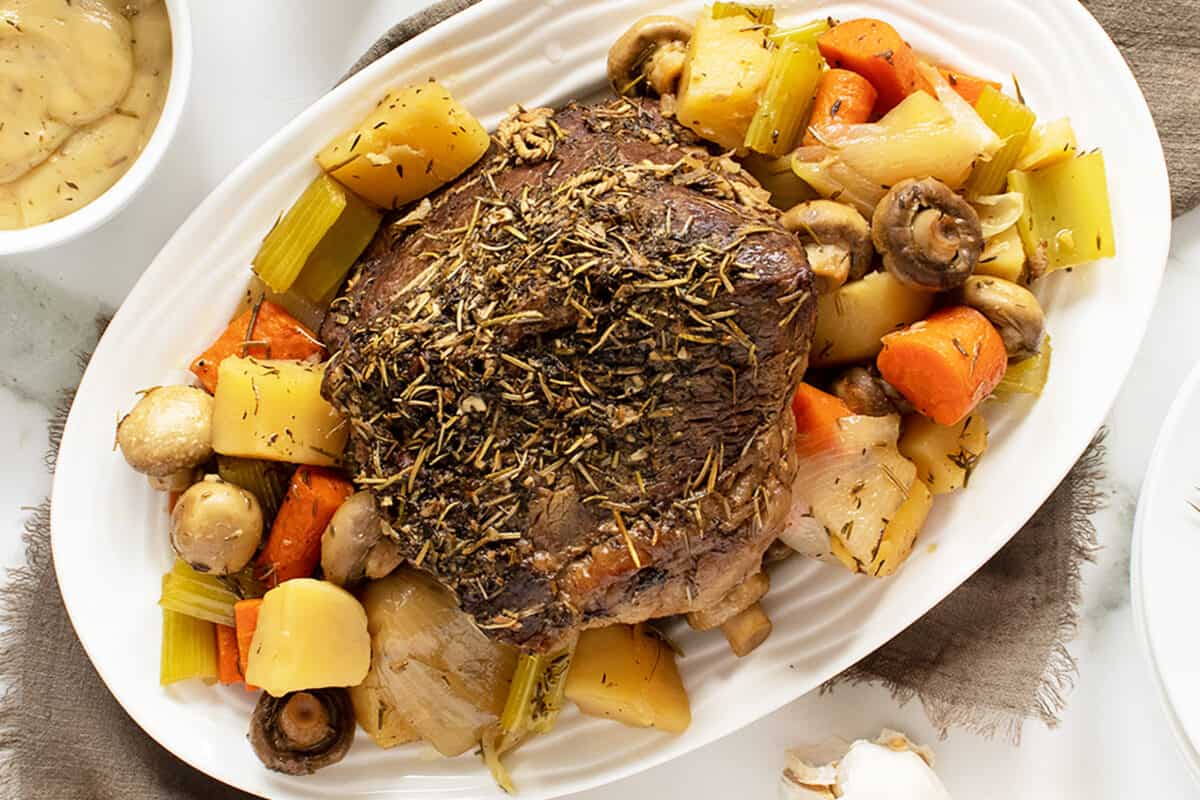 cross rib roast on a white platter with vegetables